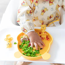 Load image into Gallery viewer, A baby in a high chair practicing self-feeding with peas on a bear-shaped plate, wearing a Bumkins Sleeved Bib: Winnie Loves Hunny.