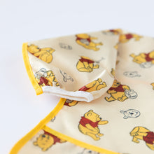 Load image into Gallery viewer, Close up of Bumkins Sleeved Bib: Winnie Loves Hunny on a white background, with focus on the white elastic cuff on the sleeve.