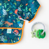 Bumkins Silicone Teething Charms: Green lays next to a blue animal-patterned sleeved bib on a white background.