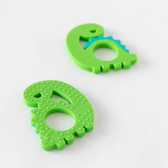Two Bumkins Silicone Teether: Dinosaur are shown on a white background; one is face-down, displaying sensory bumps on the back.