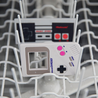 Bumkins Silicone Teether: NES™ Controller sits behind another teether in the top rack of an open dishwasher.