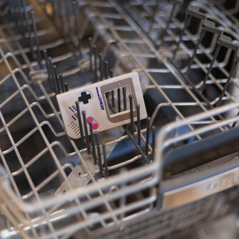 Bumkins Silicone Teether: Game Boy™ sits in the top rack of an open dishwasher.