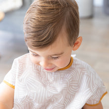 Load image into Gallery viewer, A child with light brown hair looks down while wearing a Bumkins Junior Bib: Wander.