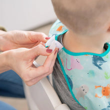 Load image into Gallery viewer, Close-up of hands adjusting the hook-and-loop closure of a Bumkins Junior Bib: Ocean Life around a child's neck.