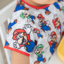 Load image into Gallery viewer, Close-up of a child's shoulder wearing a Bumkins Junior Bib: Super Mario™ & Luigi.