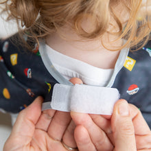 Load image into Gallery viewer, Hands fasten the hook-and-loop closure of a Bumkins Junior Bib: Super Mario™ Lineup around a child's neck.
