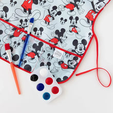 Load image into Gallery viewer, Close-up of Bumkins Short-Sleeved Smock: Mickey Mouse Classic on a white background, next to a paint palette and paintbrushes.