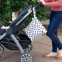 Load image into Gallery viewer, A woman pushes a stroller with a baby outdoors by greenery, with a Bumkins Wet Bag: Hearts hanging from the handle.