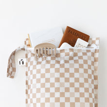 Load image into Gallery viewer, Roamio by Bumkins Wet Bag: Sand Check holds a passport, notebook, mints, and a hair clip on a white background.