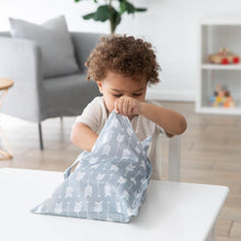 Load image into Gallery viewer, A child with curly hair opens a Bumkins Wet Bag: Arrow on a white table in a modern, cozy living room.