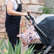 Load image into Gallery viewer, A person in black overalls pushes a stroller with a Bumkins Wet Bag: Yoga Pals hanging from the handle against a stone wall.