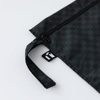 Close-up of Roamio by Bumkins Wet Bag: Rich Black on a white background, with focus on the side strap and logo tag.