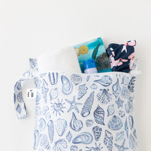 Load image into Gallery viewer, Roamio by Bumkins Wet Bag: Shells holds a towel, swimsuit, sunscreen, and book on a white background.