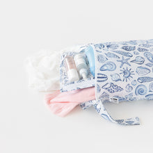 Load image into Gallery viewer, Roamio by Bumkins Wet Bag: Shells lays open on a white background with clothes and a matching pouch with toiletries inside.