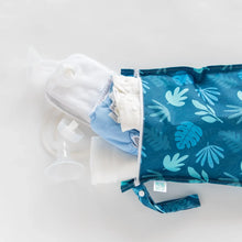 Load image into Gallery viewer, Bumkins Wet Bag: Blue Tropic holds cloth diapers and breast pump parts on a white background.