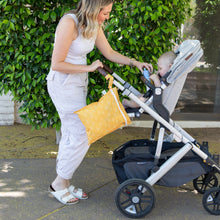 Load image into Gallery viewer, A woman in white hands an item to a baby in a stroller with a Bumkins Wet Bag: Sunshine on the handle outdoors.