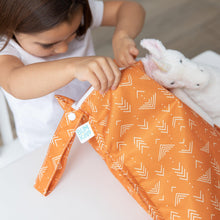 Load image into Gallery viewer, A child opens a Bumkins Wet Bag: Grounded at a white table next to a stuffed unicorn.