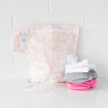 Load image into Gallery viewer, Bumkins Wet Bag: Lace sits on a white table against a white brick wall, with cloth diapers and breast pump parts in front.