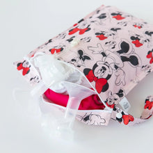 Load image into Gallery viewer, Bumkins Wet Bag: Minnie Mouse Classic sits partially open on a white background with cloth diapers and breast pump parts inside.