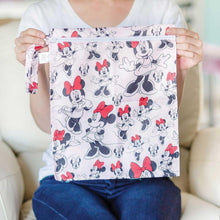Load image into Gallery viewer, A person sitting on a beige couch holds a Bumkins Wet Bag: Minnie Mouse Classic.