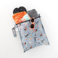 Load image into Gallery viewer, Bumkins Wet Bag: No Tricks, Just Treats holds orange swimwear, a towel, flip-flops, and orange sunglasses on a white background.
