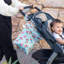 Load image into Gallery viewer, A person strolls with a baby in a stroller outdoors as a Bumkins Wet Bag: Disney Princess Ariel hangs from the handle.