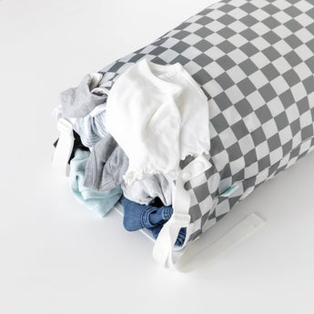Bumkins Extra Large Wet Bag: Charcoal Check with clothes spilling out, including a white top and blue jeans, on a white background.