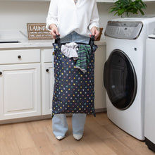 Load image into Gallery viewer, In the laundry room, a person holds a Bumkins Extra Large Wet Bag: Super Mario™ Lineup with snap handles, filled with clothes.