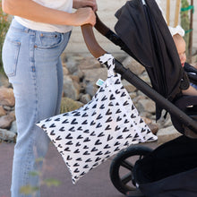 Load image into Gallery viewer, A parent pushes a stroller with a Bumkins Wet/Dry Bag: Hearts, made of waterproof fabric, hanging from the handle.