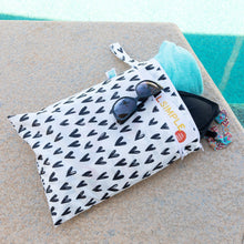 Load image into Gallery viewer, Bumkins Wet/Dry Bag: Hearts holds sunglasses, a turquoise towel, and a swimsuit by a pool.