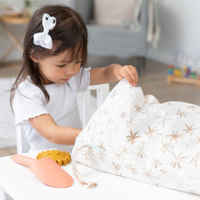 Load image into Gallery viewer, A young girl in a white bow opens a Bumkins Wet/Dry Bag: Palm Daze at a white table beside a toy shovel and sand toy.