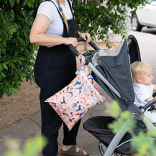 Load image into Gallery viewer, A person in black overalls pushes a stroller with a child, with a colorful Bumkins Wet/Dry Bag: Yoga Pals on the handle.