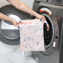 Load image into Gallery viewer, A person holds a Bumkins Wet/Dry Bag: Yoga Pals in front of a front-loading washing machine.