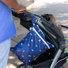 Load image into Gallery viewer, A person pushes a stroller with a child inside; a Bumkins Wet/Dry Bag: Evil Eye, made from waterproof fabric, hangs from the handle.