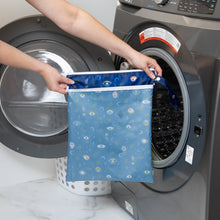 Load image into Gallery viewer, A person holds a Bumkins Wet/Dry Bag: Evil Eye in front of an open washing machine.