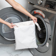 Load image into Gallery viewer, A person holds a Bumkins Wet/Dry Bag: Wander in front of an open front-loading washing machine.