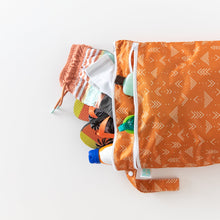Load image into Gallery viewer, Bumkins Wet/Dry Bag: Grounded, filled with swimwear, flip-flops, sunscreen, and goggles, lays on a white background.