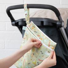 Load image into Gallery viewer, A hand zips a Bumkins Wet/Dry Bag: Camp Gear attached to a stroller in front of a white brick wall.