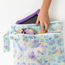 Load image into Gallery viewer, A child puts goggles, flower print clothes, and a purple tablet into a colorful Bumkins Wet/Dry Bag: Aloha Stitch on a white table.