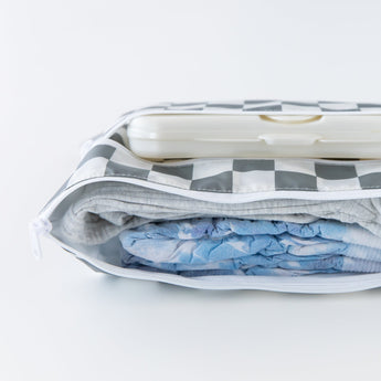 Bumkins Wet/Dry Clutch: Charcoal Check lays open on a white background with diapers, clothes, and wipes inside.