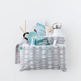 Bumkins Wet/Dry Clutch: Lunar Phase holds a water bottle, sleep mask, notebook, and more on a white background.
