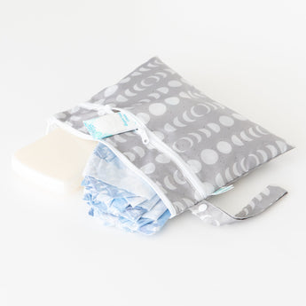 Bumkins Wet/Dry Clutch: Lunar Phase holds a diaper, wipes, and cream on a white background.