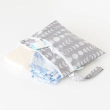 Load image into Gallery viewer, Bumkins Wet/Dry Clutch: Lunar Phase holds a diaper, wipes, and cream on a white background.