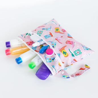 Bumkins Wet/Dry Clutch: Boots opens to show travel-sized bottles and containers on a white background.