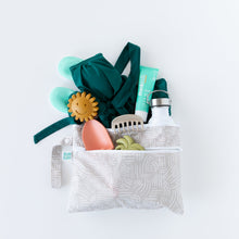 Load image into Gallery viewer, Bumkins Wet/Dry Clutch: Wander on white background with a swimsuit, turquoise shoes, sippy cup, sunscreen, and toys.