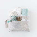 Bumkins Wet/Dry Clutch: Wander holds a stuffed dragon, clothes, hair clip, and wipes on a white background.
