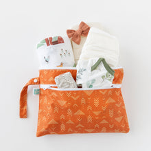 Load image into Gallery viewer, Bumkins Wet/Dry Clutch: Grounded holds a onesie, blanket, wipes, diapers, and a bow on a white background.