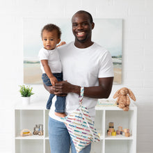 Load image into Gallery viewer, A man holding toddler and Bumkins Wet/Dry Clutch: Mickey & Friends Varsity, both in white shirts, in room with white walls and toys.