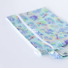 Load image into Gallery viewer, Bumkins Wet/Dry Clutch: Aloha Stitch lays on a white background, with focus on the zippers and snap closure of the handle.