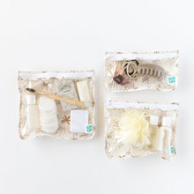 Load image into Gallery viewer, Bumkins Clear Travel Bag 3 Pack: Palm Daze holds toiletries like cotton pads, shampoo, a hairbrush, and a clip on a white background.